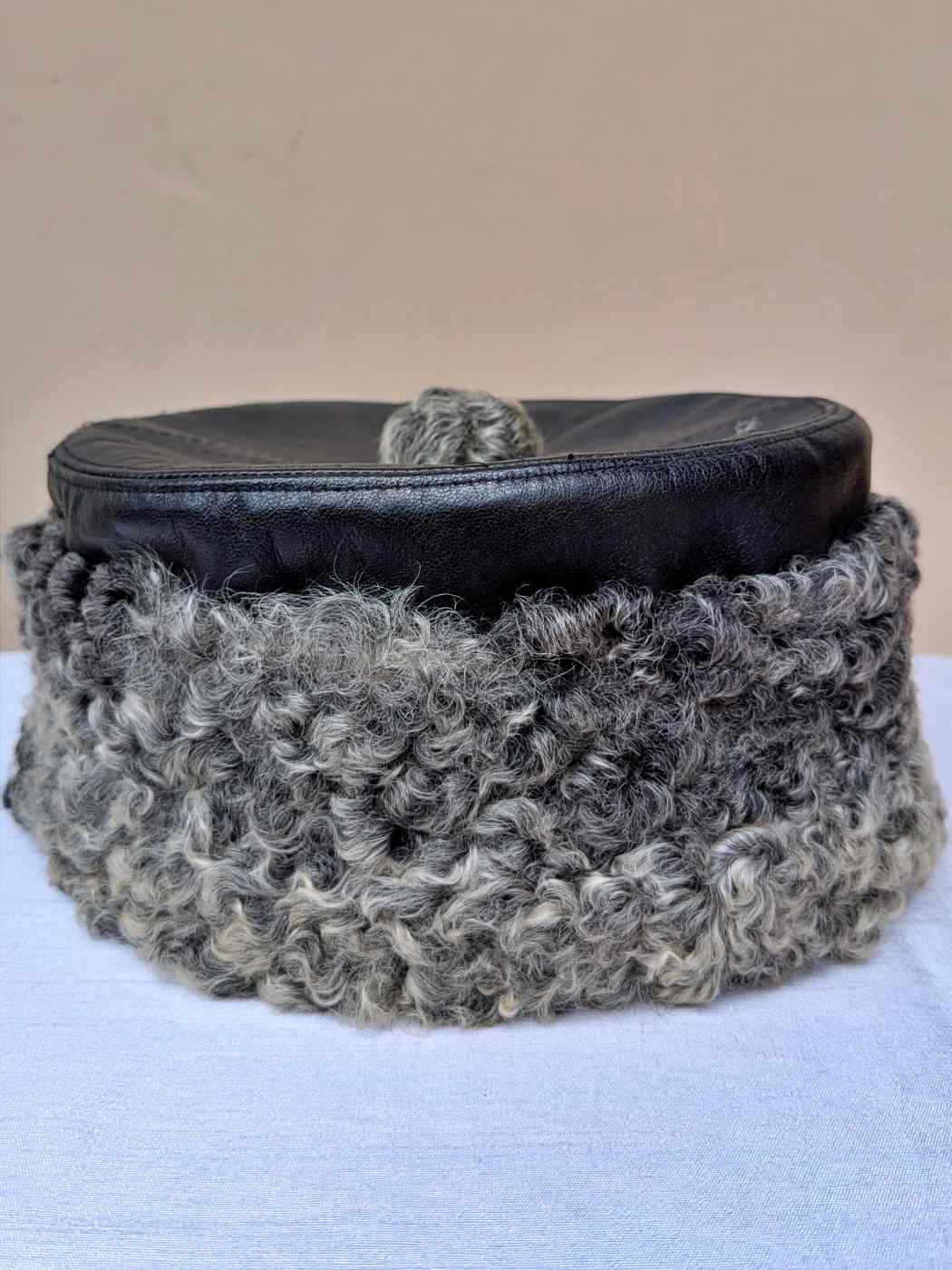 Black leather cap in karakul fur