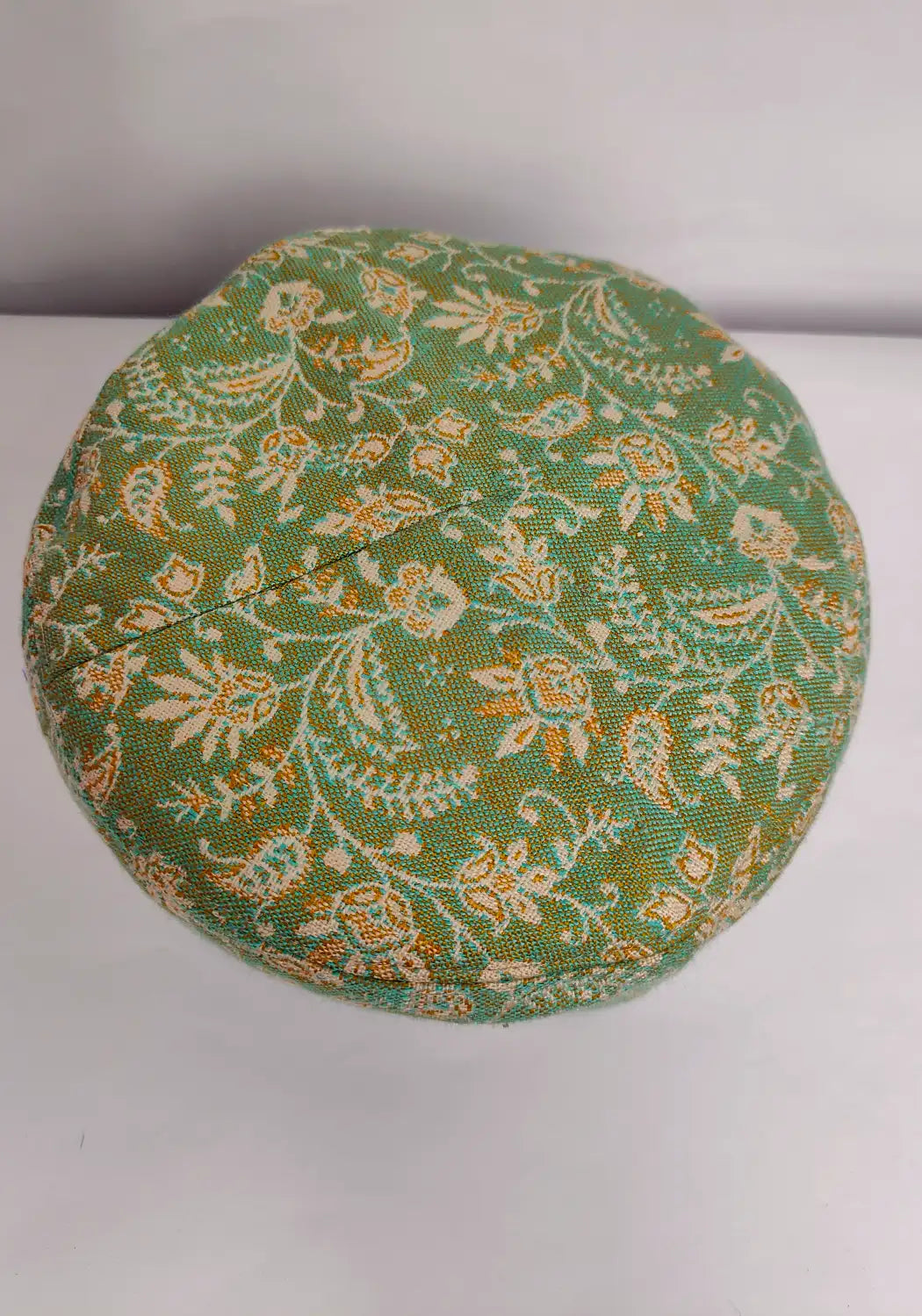 Top side of green kani cap in badami kani woven pattern 