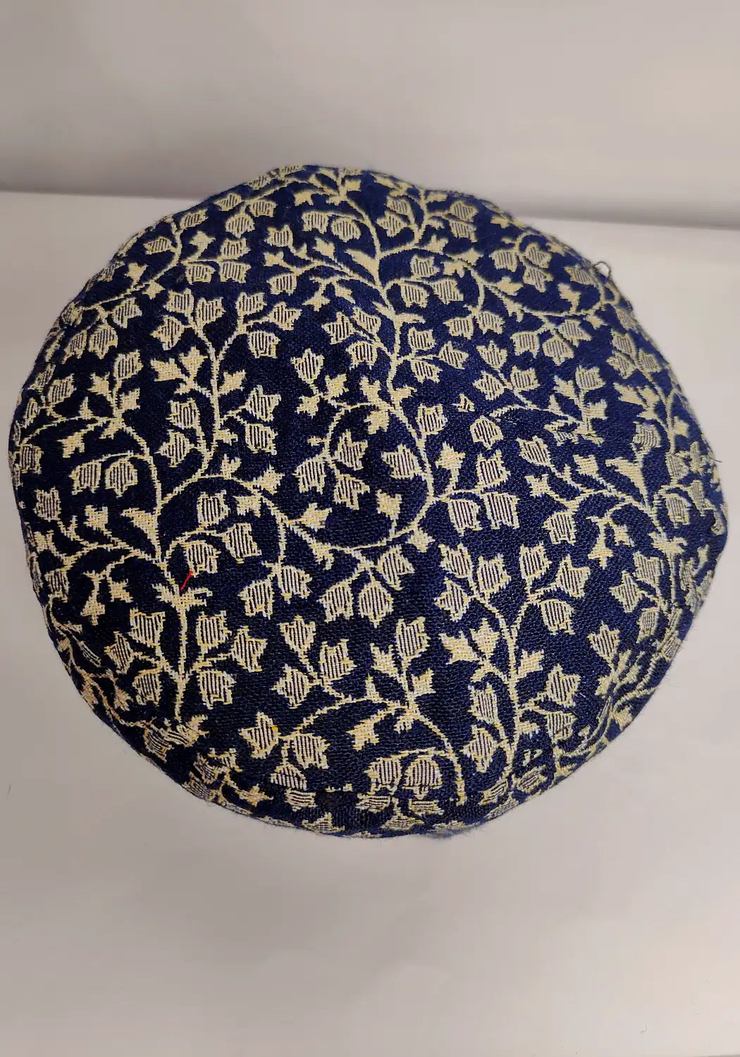 floral detailing on the top side of the dark blue traditional kani cap