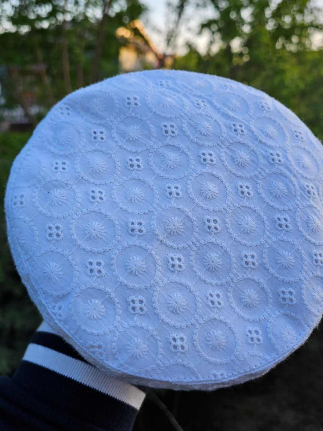 white cotton cap in hakoba pattern held against a natural background in Kashmir