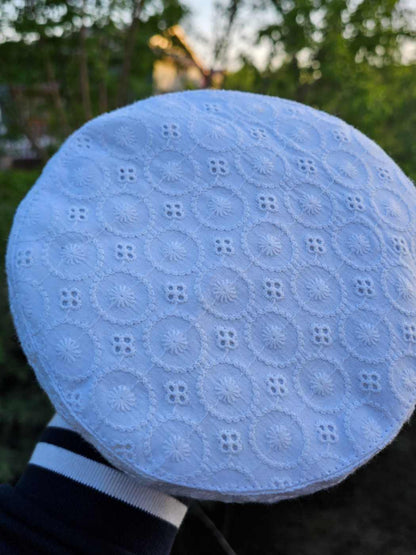 white cotton cap in hakoba pattern held against a natural background in Kashmir